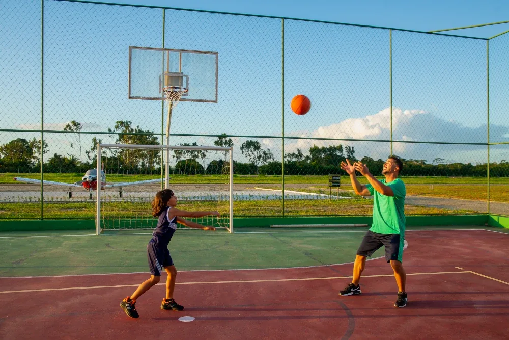Adulto e criança jogando basquete com avião ao fundo