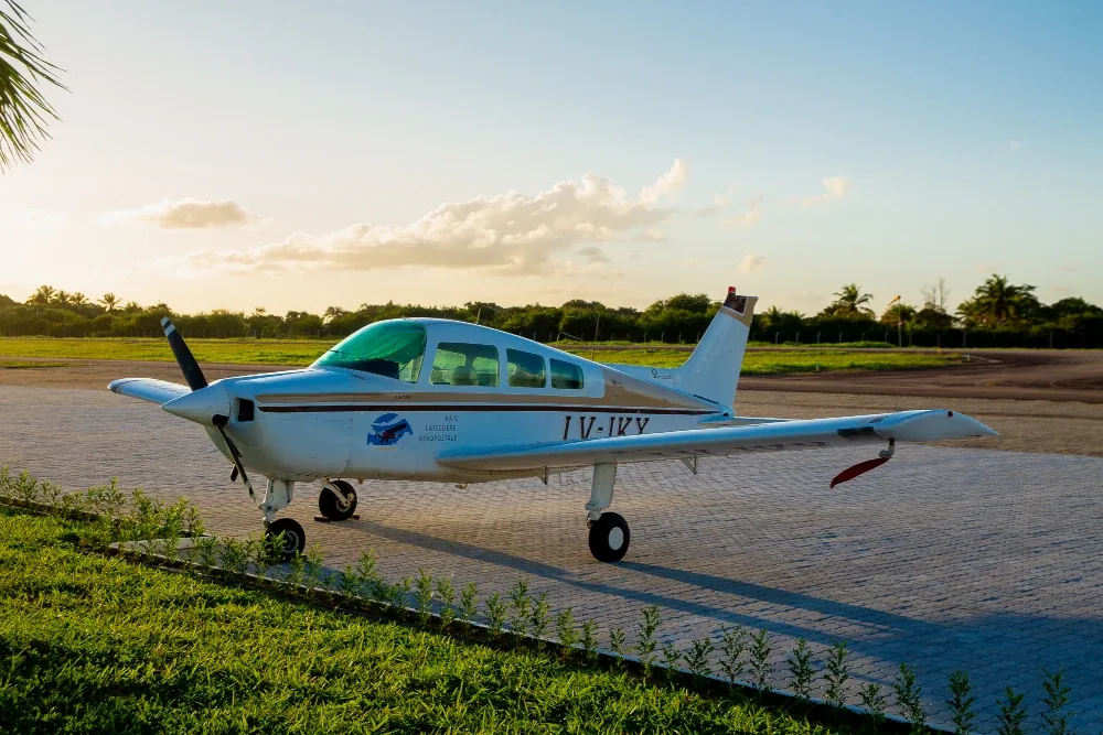 Avião monomotor branco estacionado no pátio ao entardecer