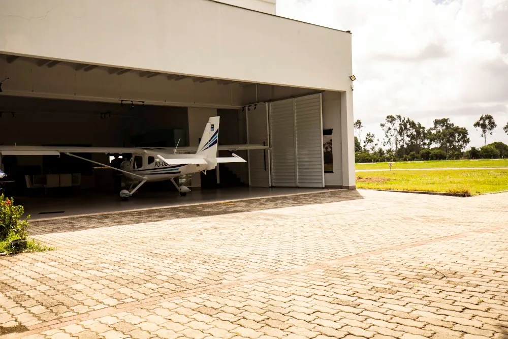 Avião monomotor branco em hangar aberto
