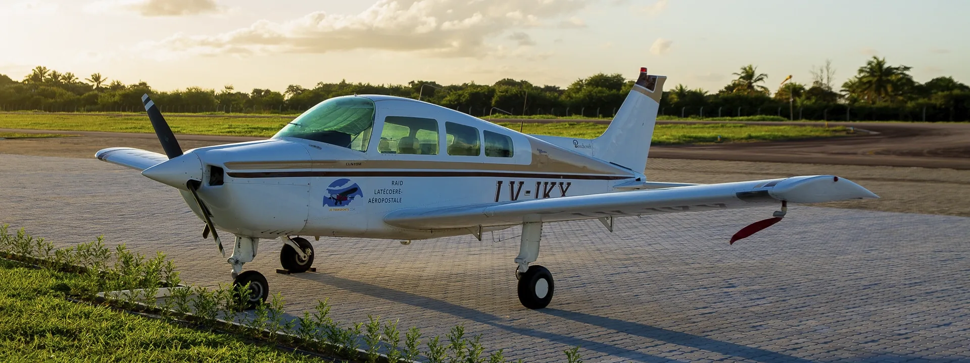 Avião monomotor branco estacionado no pátio ao entardecer